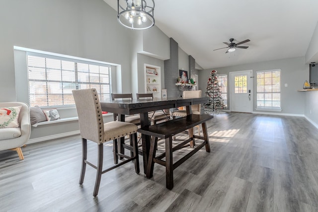 dining room with ceiling fan with notable chandelier, lofted ceiling, hardwood / wood-style floors, and a healthy amount of sunlight