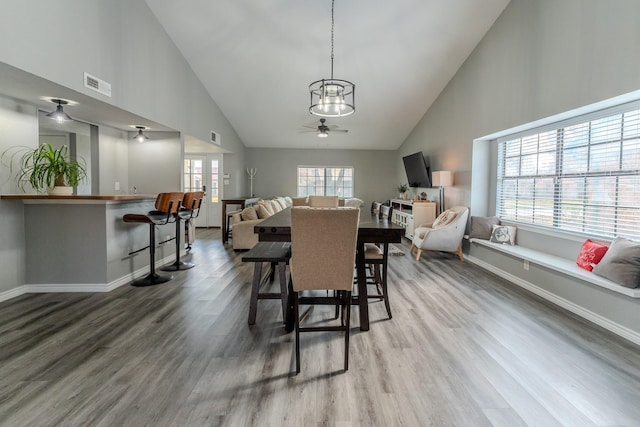 dining area with high vaulted ceiling, ceiling fan, wood-type flooring, and plenty of natural light