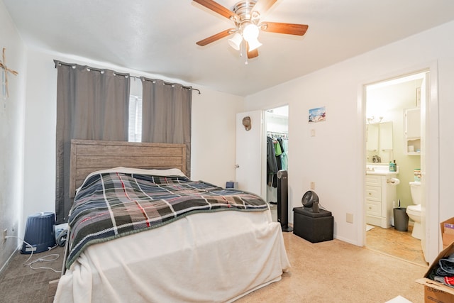 carpeted bedroom featuring a walk in closet, ensuite bath, ceiling fan, sink, and a closet