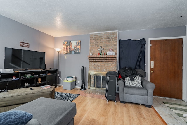 living room featuring a fireplace, wood-type flooring, and a textured ceiling