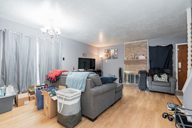 living room featuring a notable chandelier, a fireplace, a textured ceiling, and light hardwood / wood-style flooring