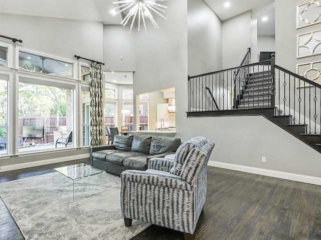 living room featuring dark hardwood / wood-style flooring, a notable chandelier, a towering ceiling, and sink