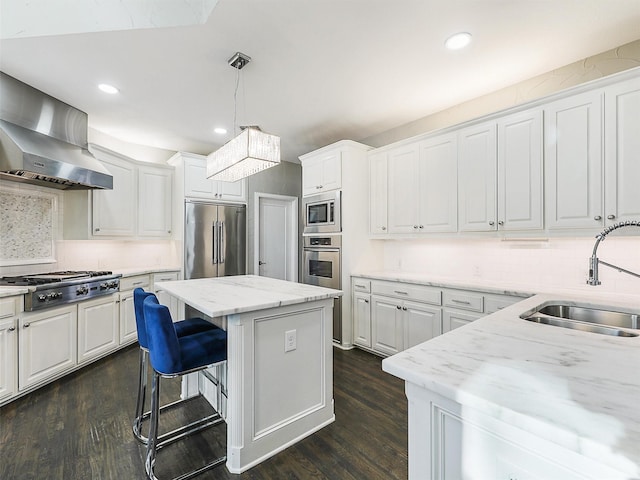 kitchen with built in appliances, a center island, white cabinets, and wall chimney exhaust hood