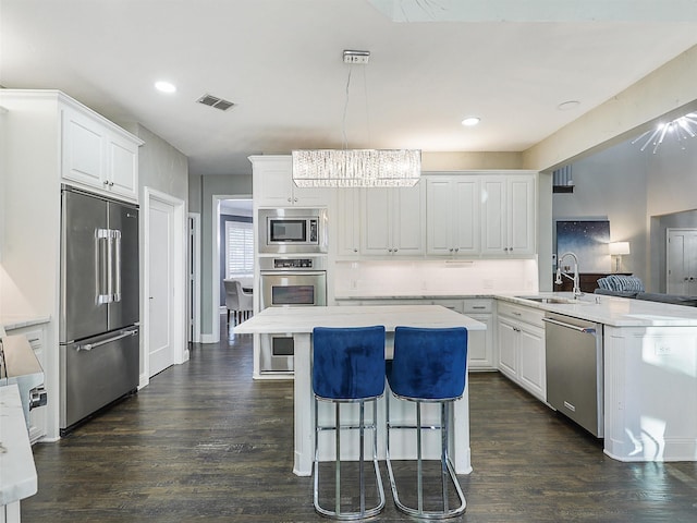 kitchen with white cabinetry, sink, built in appliances, and kitchen peninsula