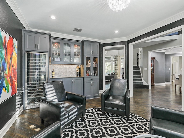 living room featuring crown molding, dark wood-type flooring, bar, and a chandelier