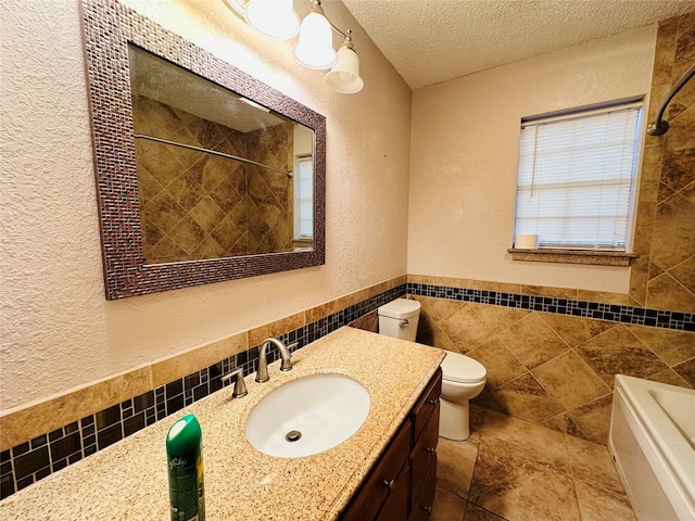 full bathroom with vanity, toilet, a textured ceiling, independent shower and bath, and tile walls