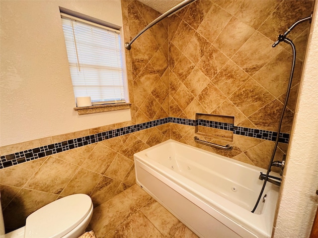 bathroom featuring tiled shower / bath, toilet, tile walls, and tile patterned floors