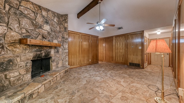 unfurnished living room with beam ceiling, ceiling fan, a stone fireplace, high vaulted ceiling, and a textured ceiling