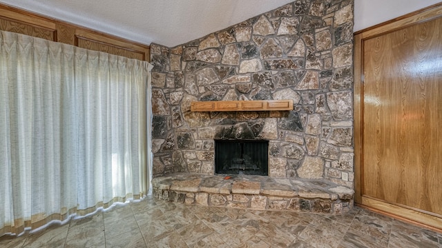 unfurnished living room with vaulted ceiling, a fireplace, and a textured ceiling