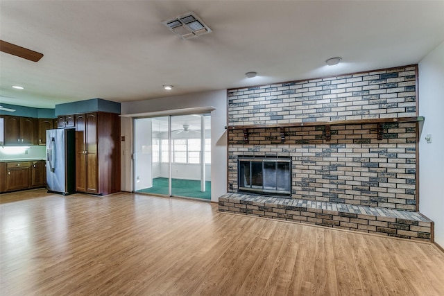 unfurnished living room with a brick fireplace and light hardwood / wood-style flooring