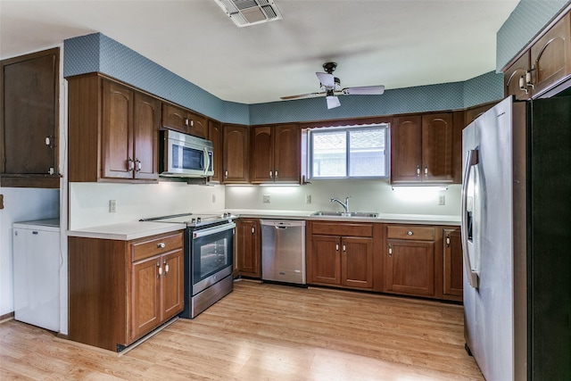 kitchen featuring stainless steel appliances, ceiling fan, light hardwood / wood-style floors, and sink