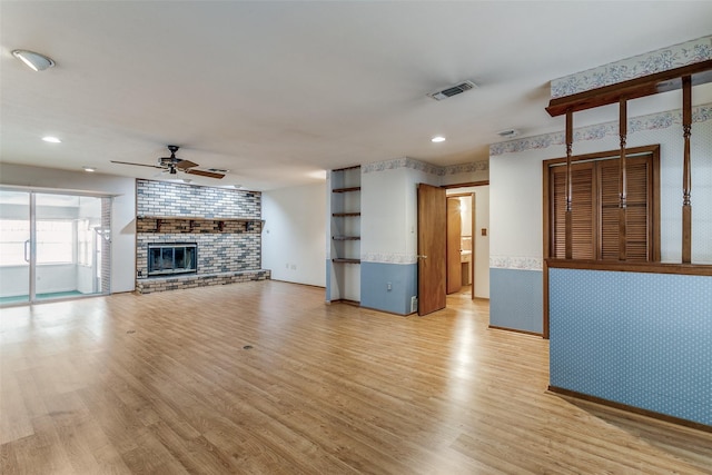 unfurnished living room with ceiling fan, a fireplace, and light wood-type flooring