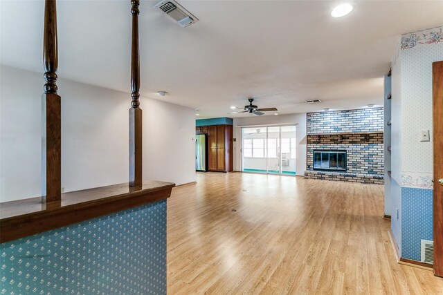 unfurnished living room with a fireplace, light hardwood / wood-style floors, and ceiling fan