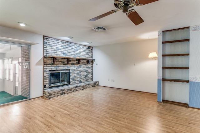 unfurnished living room featuring a brick fireplace, ceiling fan, and light wood-type flooring