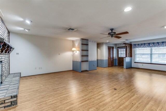 unfurnished living room featuring hardwood / wood-style flooring, ceiling fan, and a brick fireplace