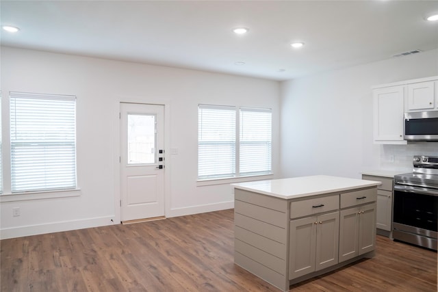 kitchen featuring a center island, dark hardwood / wood-style flooring, gray cabinets, stainless steel appliances, and decorative backsplash