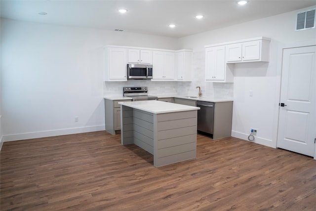 kitchen with white cabinets, a center island, dark wood-type flooring, stainless steel appliances, and sink