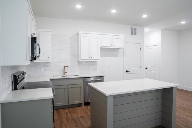 kitchen with appliances with stainless steel finishes, sink, gray cabinetry, and a kitchen island