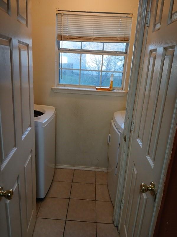 laundry room with washer and dryer and light tile patterned floors