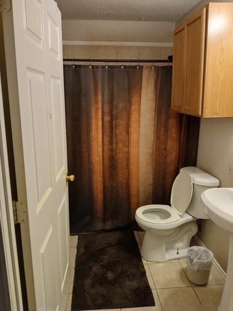 bathroom with tile patterned flooring, a textured ceiling, and toilet