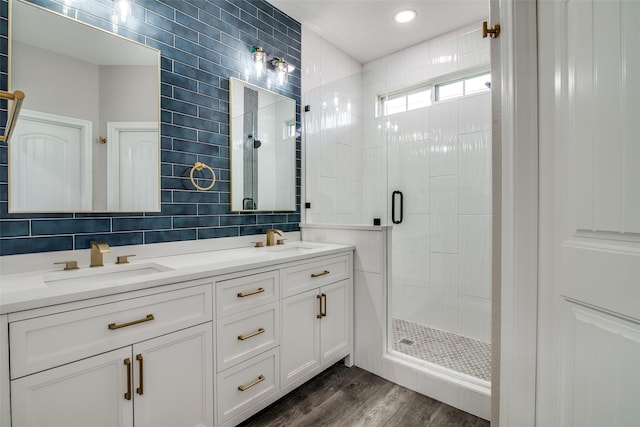 bathroom with vanity, a shower with door, backsplash, hardwood / wood-style flooring, and tile walls