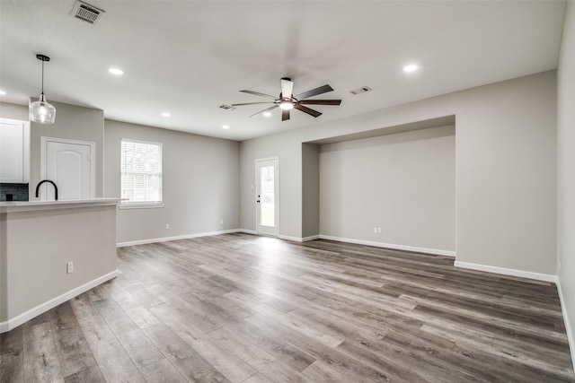 unfurnished living room featuring ceiling fan and wood-type flooring