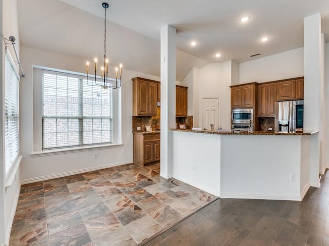 kitchen featuring tasteful backsplash, vaulted ceiling, hanging light fixtures, dark stone counters, and stainless steel appliances