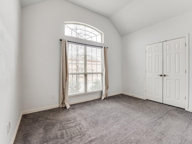 unfurnished bedroom featuring multiple windows, vaulted ceiling, and carpet flooring