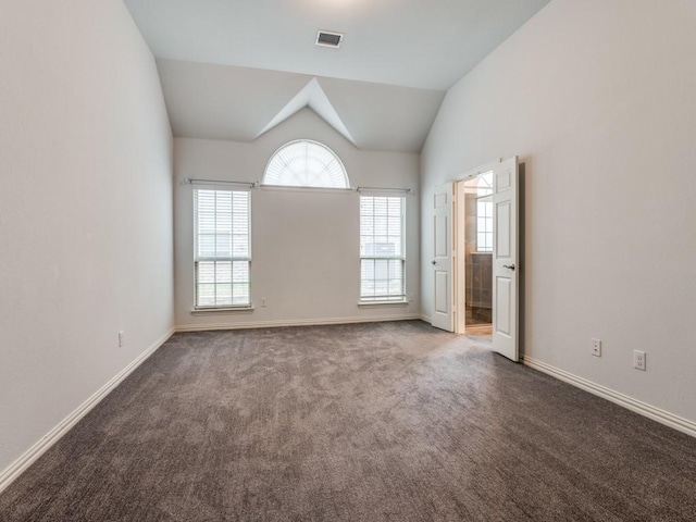 unfurnished room with a healthy amount of sunlight, lofted ceiling, and carpet floors