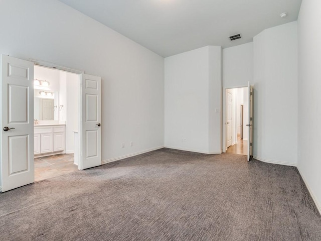 unfurnished bedroom featuring light colored carpet and connected bathroom