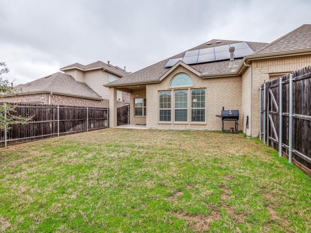 back of house with a lawn and solar panels