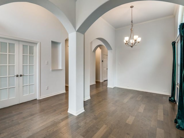 unfurnished room featuring dark hardwood / wood-style flooring, ornamental molding, french doors, and an inviting chandelier