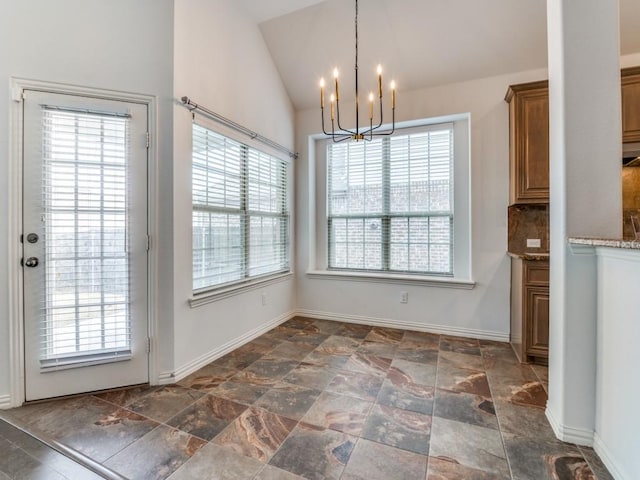 unfurnished dining area featuring plenty of natural light, lofted ceiling, and an inviting chandelier