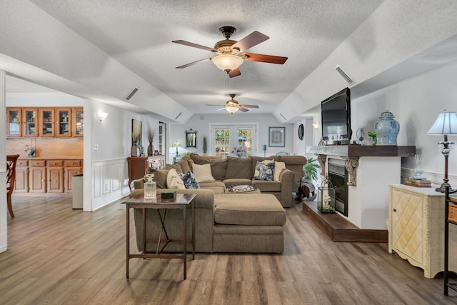 living room with hardwood / wood-style flooring, vaulted ceiling, and a textured ceiling