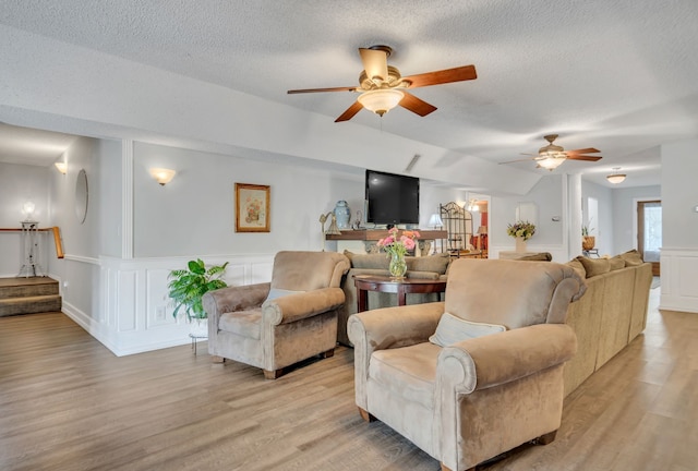 living room featuring ceiling fan, a textured ceiling, and light wood-type flooring