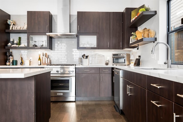 kitchen featuring backsplash, high end stainless steel range oven, sink, wall chimney range hood, and dark hardwood / wood-style floors