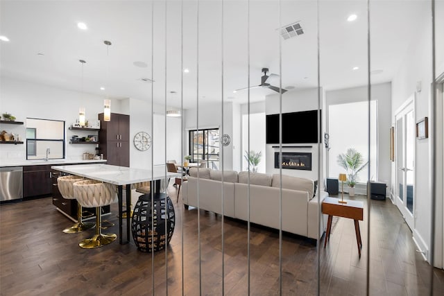 living room featuring ceiling fan, sink, and dark hardwood / wood-style floors