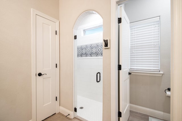 bathroom with a shower stall and baseboards