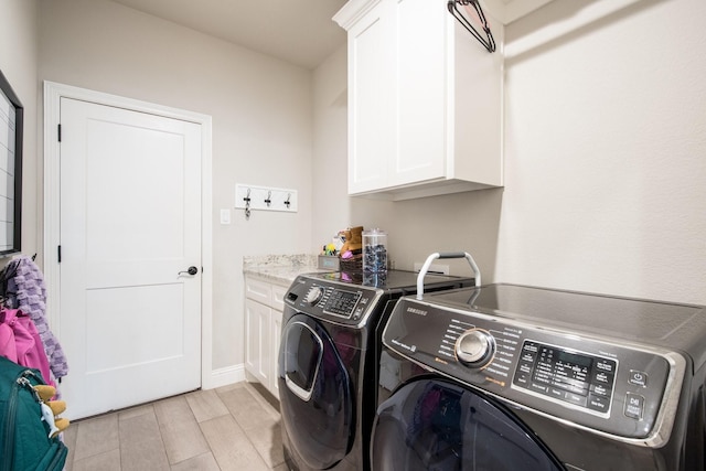 clothes washing area featuring washing machine and clothes dryer, cabinet space, baseboards, and wood tiled floor