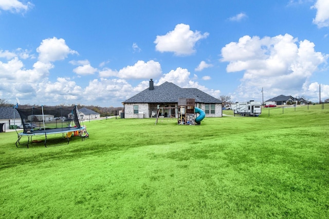 view of yard featuring fence, a trampoline, and a playground