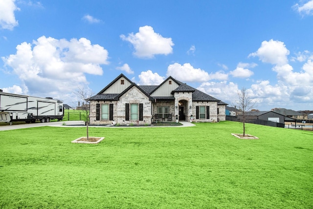 view of front of property with a front lawn, fence, stone siding, and roof with shingles