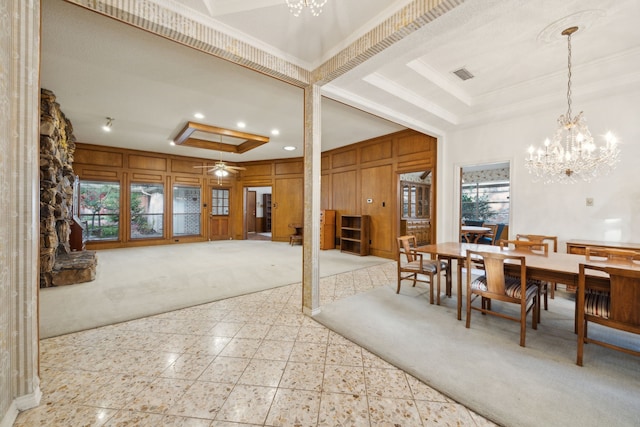 carpeted dining room with ceiling fan with notable chandelier, a raised ceiling, and a wealth of natural light