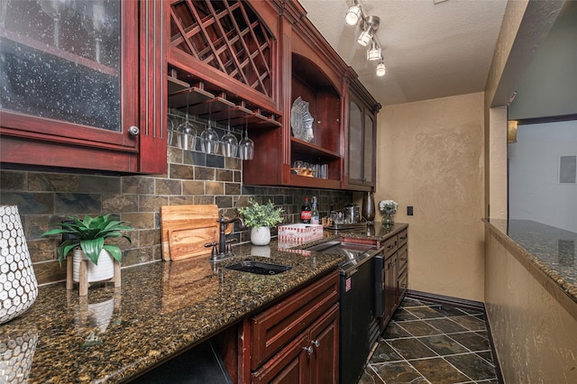 kitchen with decorative backsplash, a textured ceiling, dark stone countertops, and sink