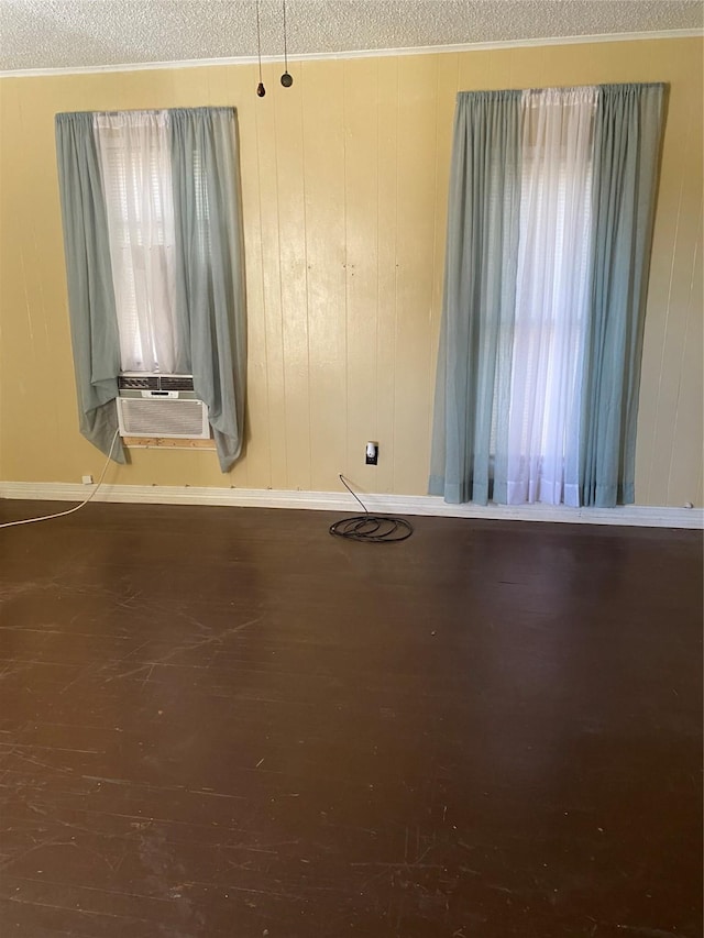 empty room with wood walls, dark wood-type flooring, and a textured ceiling