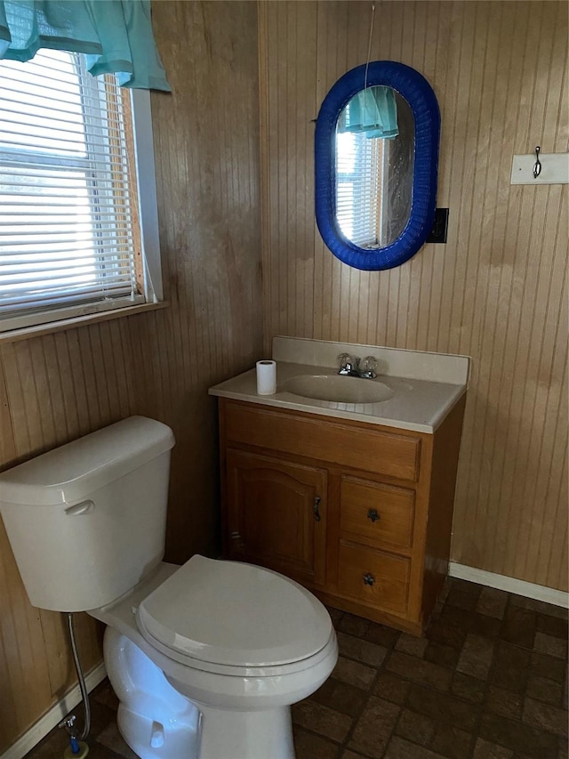 bathroom featuring vanity, toilet, and wood walls