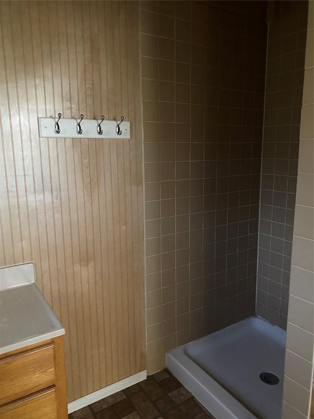 bathroom featuring vanity, wood walls, and a tile shower