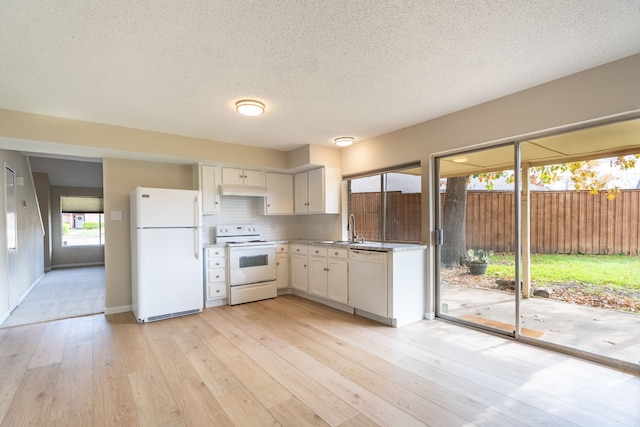 kitchen with backsplash, white appliances, sink, white cabinets, and light hardwood / wood-style floors