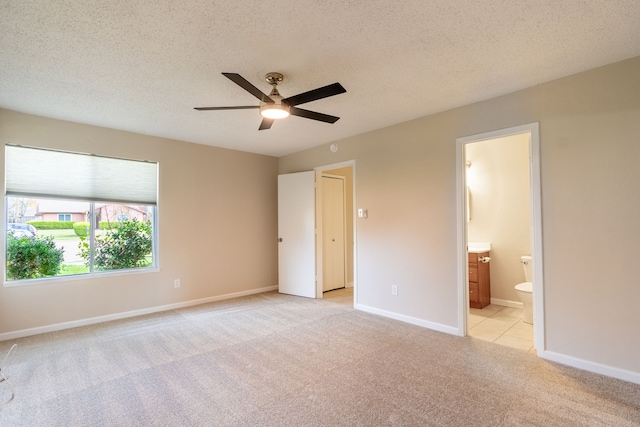 unfurnished bedroom with ensuite bathroom, ceiling fan, light carpet, and a textured ceiling