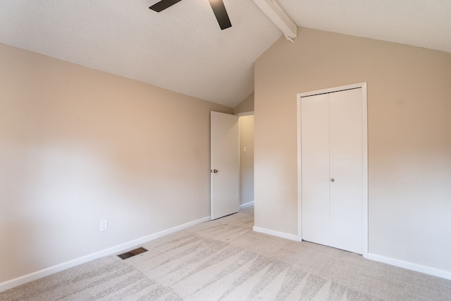 unfurnished bedroom with light carpet, lofted ceiling with beams, a closet, and ceiling fan