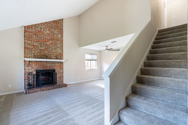 stairway featuring carpet flooring, a brick fireplace, high vaulted ceiling, and ceiling fan